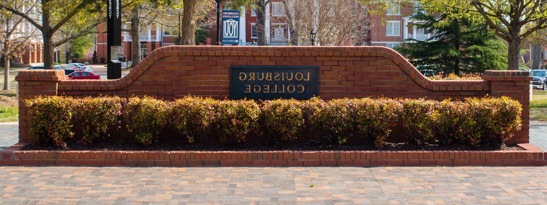 a brick wall on 校园 that reads Louisburg College